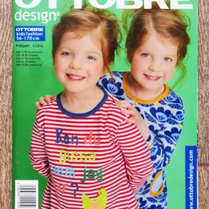 May include: The Ottobre Design magazine cover shows two smiling girls. One is in a red and white striped top with text and a yellow chicken. The other wears a blue floral print top. The magazine title is in large white letters.
