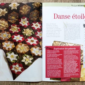 May include: A colorful quilt with a star pattern, made with fabric scraps. The quilt is called "Danse &eacute;toil&eacute;e" and is 84 cm wide. The quilt is displayed on a table with apples in a white bowl.