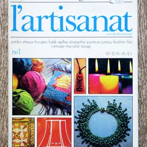 May include: Magazine cover titled "de fil en aiguille" with the word "l'artisanat" in blue. The cover displays craft projects such as candles, jewellery, and textiles. The magazine is number 1.