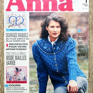 Könnte beinhalten: Ein Magazincover mit einer Frau, die einen blauen Strickpullover mit weißem Kragen und Knöpfen trägt. Das Magazin heißt "Anna" und handelt vom Stricken und Häkeln. Das Cover zeigt auch ein kleines Bild eines gestrickten Kragens und ein größeres Bild einer gestrickten Tischdecke.