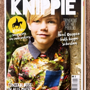 May include: A magazine cover featuring a young boy wearing a colorful shirt with a fox print. The magazine is titled "Knippie" and has the text "DIYsint surprises and cadeautjes" and "Tunikblouse in alle maten".