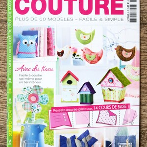 May include: A magazine cover with the title "Couture" in pink letters. The cover features a variety of colourful fabric crafts, including birds, a flower, a birdhouse, and cushions. The text "Plus de 60 modèles - Facile & Simple" is also visible on the cover.