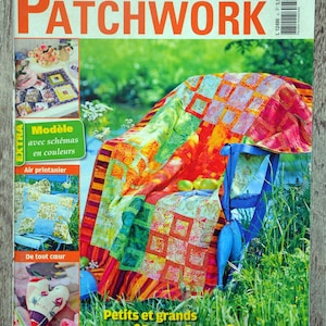 Op de afbeelding: Een tijdschriftcover met een kleurrijk patchwork-deken op een blauwe stoel in een grasrijke omgeving. Het tijdschrift heet "Sabrina Patchwork" en de tekst op de omslag is "Petits et grands quilts de rêve".