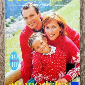 Peut inclure: Couverture du catalogue "Phildar" avec une famille portant des pulls rouges. Le titre "Phildar Créations" est en jaune. Le texte français comprend "40 Modèles 10F" et "40 modèles pour un hiver tout en couleur". L'image présente une famille souriante dans un cadre naturel.