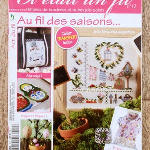 May include: A pink and white magazine titled Il etait un fil number 12, featuring embroidery patterns and craft projects. The cover displays various needlework designs, including a heart-shaped wreath, a bag, and seasonal motifs.