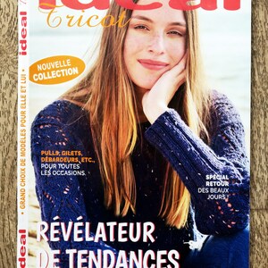 Może przedstawiać: Okładka magazynu z kobietą w granatowym swetrze. Tytuł "ideal tricot" jest w kolorze czerwonym i złotym. Tekst zawiera "Nouvelle Collection" i "Révélateur de Tendances".