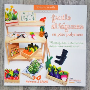 Peut inclure: Couverture de livre illustrant un stand miniature de fruits et légumes. Le titre est "Fruits et légumes en pâte polymère" et le sous-titre est "Mettez des vitamines dans vos créations!" Le livre est de Nolwenn Le Grand.