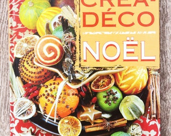Könnte beinhalten: Ein Buchcover mit gelbem Hintergrund und rotem Text, der "Crea-Deco Noel" von Christel Claudius lautet. Das Cover zeigt eine Nahaufnahme eines Tellers, der mit Orangen, Limetten, Zimtstangen, Sternanis und anderen Weihnachtsdekorationen gefüllt ist.