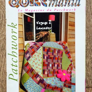 Op de afbeelding: Een tijdschriftcover voor Quiltmania, een patchworkmagazine. De cover toont een kleurrijk patchworkdeken met een roze bloem erop. De tekst op de cover luidt "Quiltmania, Le Magazine du Patchwork, Voyage à Lancaster".