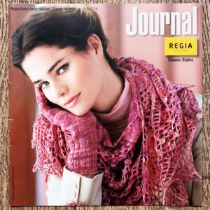 Peut inclure: Couverture de magazine avec une femme portant un châle et des gants en tricot rose. Le titre "Journal" est en blanc. Le logo Regia et "Classic Styles" sont également visibles. Le magazine s'intitule "Regia Extra Twist Merino Classic Styles".