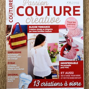以下が含まれることがあります： 「Passion Couture Creative」というタイトルの雑誌の表紙。赤と金の文字で書かれています。表紙には、ハンドバッグ、ブラウス、歯の形をしたポーチなど、縫製プロジェクトの写真が掲載されています。「13 créations à vivre」というテキストが含まれています。