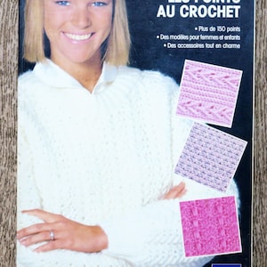 Peut inclure: Couverture de livre "LES POINTS AU CROCHET" avec une femme souriante en pull blanc. Le livre présente des échantillons de points de crochet roses et violets, avec le logo PHILDAR.