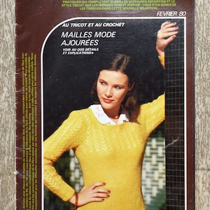 Könnte beinhalten: Ein Vintage-Magazincover mit einer Frau, die einen gelben Strickpullover mit weißem Kragen trägt. Das Magazin heißt "Tricot-Crochet" und der Titeltext lautet "Mailles Mode Ajourées" mit dem Untertitel "Au Tricot et Au Crochet". Das Magazincover ist mit "Februar 80" datiert.
