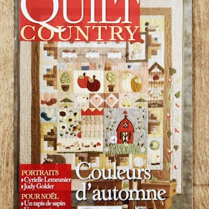 Peut inclure: Une couverture de magazine "QUILT COUNTRY" avec un patchwork coloré. Le patchwork présente des motifs d'automne, comme des pommes et une grange rouge. Le titre "Couleurs d'automne" est également présent, ainsi que d'autres textes.