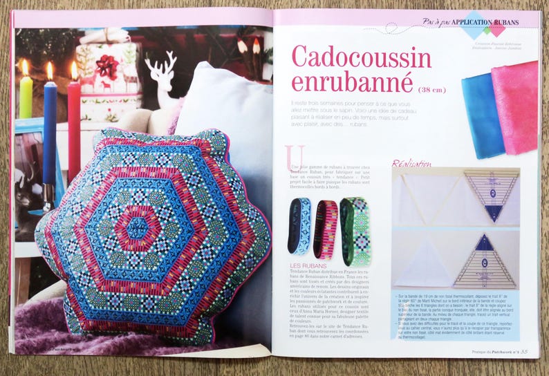 May include: A close-up of a colorful pillow with a geometric pattern. The pillow is blue, green, pink, and white. The pillow is 38 cm wide. The text "Cadocousssin enrubann&eacute;" is visible in the image.