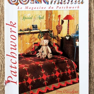 Op de afbeelding: De cover van het tijdschrift "Quiltmania" toont een patchwork quilt met een rood en bruin sterrenpatroon. De titel van het tijdschrift staat in kleurrijke letters, met "Spécial Noël" boven de quilt. Een teddybeer zit op de quilt.
