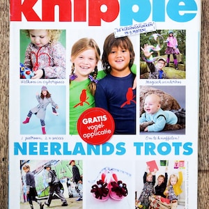 May include: A magazine cover with the title "Knippie" in large red and blue letters. The cover features photos of children, including a girl in a coat and a boy in a blue shirt. Text includes "38 clothing items in 6 sizes" and "Neerlands Trots."