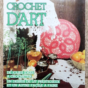 May include: A vintage magazine cover with the title "TRICOT SELECTION CROCHET D'ART" in pink and green. The cover features a white crocheted lampshade, a red crocheted cushion, and a white crocheted doily. There is also a pitcher of orange juice and a basket of oranges.