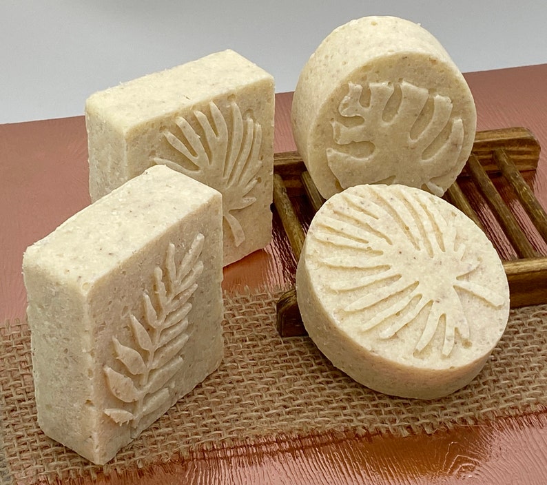 May include: Four handmade soap bars with a natural, off-white color. Each bar features a different embossed design of a tropical leaf.