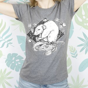 May include: A gray t-shirt with a black and white illustration of a rat with a crescent moon and stars in the background.
