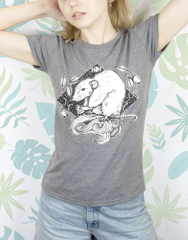 May include: A gray t-shirt with a black and white illustration of a rat with a crescent moon and stars in the background.
