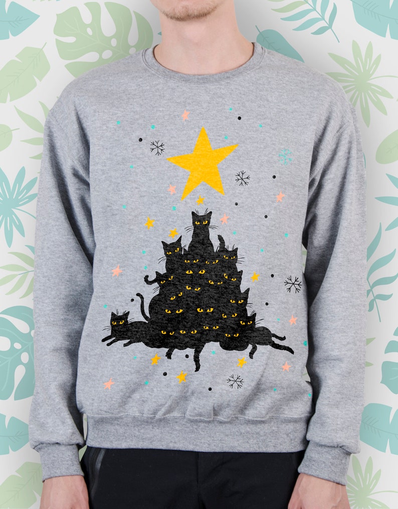 May include: A gray sweatshirt with a black cat Christmas tree design. The tree is made up of stacked black cats with yellow eyes and a yellow star on top. The background is a light gray with snowflakes and stars.