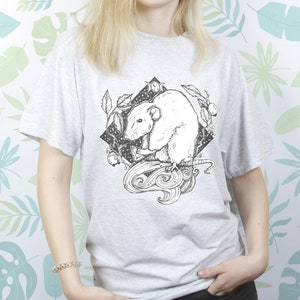May include: A gray t-shirt with a black and white illustration of a rat with a crescent moon and stars in the background.
