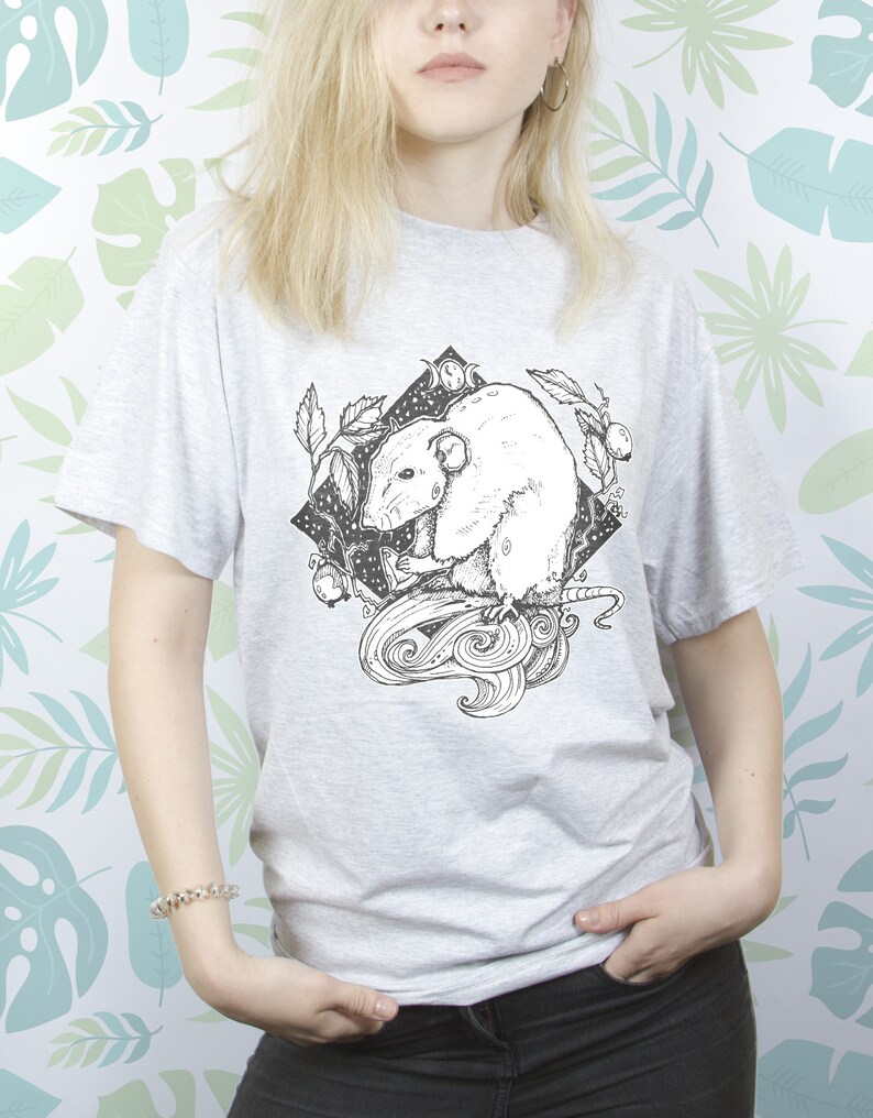 May include: A gray t-shirt with a black and white illustration of a rat with a crescent moon and stars in the background.