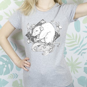 May include: A gray t-shirt with a black and white illustration of a rat in a circle with a crescent moon and stars. The rat is surrounded by leaves and vines.