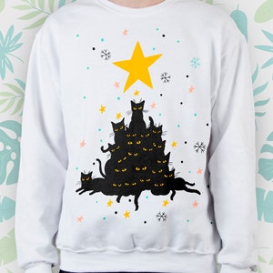 May include: White sweatshirt with a black cat Christmas tree design. The tree is made up of black cats stacked on top of each other with a yellow star on top. The background is white with snowflakes and stars.