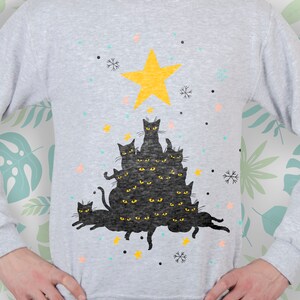 May include: A gray sweatshirt with a black cat Christmas tree design. The tree is made up of multiple black cats stacked on top of each other, with a yellow star on top. The design is surrounded by snowflakes and stars.