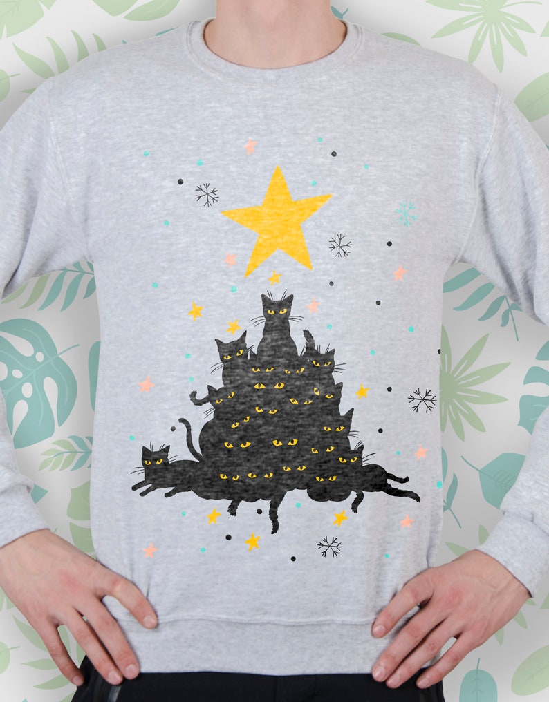 May include: A gray sweatshirt with a black cat Christmas tree design. The tree is made up of multiple black cats stacked on top of each other, with a yellow star on top. The design is surrounded by snowflakes and stars.