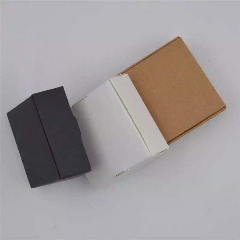 K&ouml;nnte beinhalten: Drei Geschenkboxen in verschiedenen Farben: Schwarz, Wei&szlig; und Braun. Die Boxen sind aus Pappe und haben ein schlichtes Design.