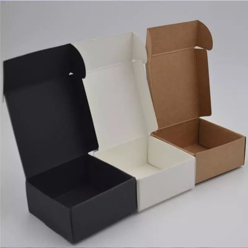 K&ouml;nnte beinhalten: Drei leere Geschenkboxen, eine schwarze, eine wei&szlig;e und eine braune. Die Boxen sind offen und haben eine quadratische Form.