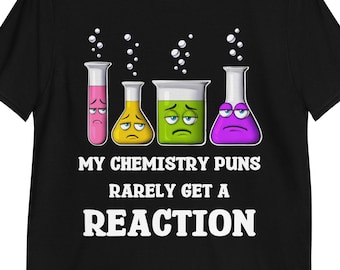 May include: Black t-shirt featuring a graphic of four cartoon chemistry beakers with sad faces. The text "MY CHEMISTRY PUNS RARELY GET A REACTION" is printed below the beakers in white.
