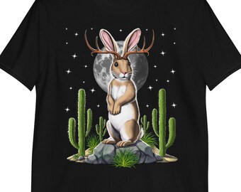Könnte beinhalten: Ein schwarzes T-Shirt mit einem Aufdruck eines braunen Kaninchens mit Geweih, das auf einem Felsen steht, umgeben von Kakteen unter einem Vollmond.