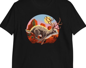 May include: Black t-shirt with a graphic of a desert scene featuring a running rabbit with antlers. The rabbit is brown and white with a pink and orange sunset in the background.