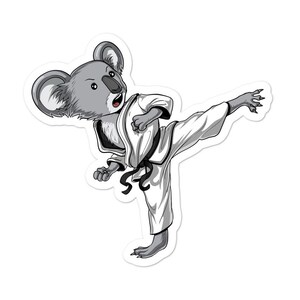 May include: A cartoon koala wearing a white karate uniform with a black belt, kicking with its right leg.