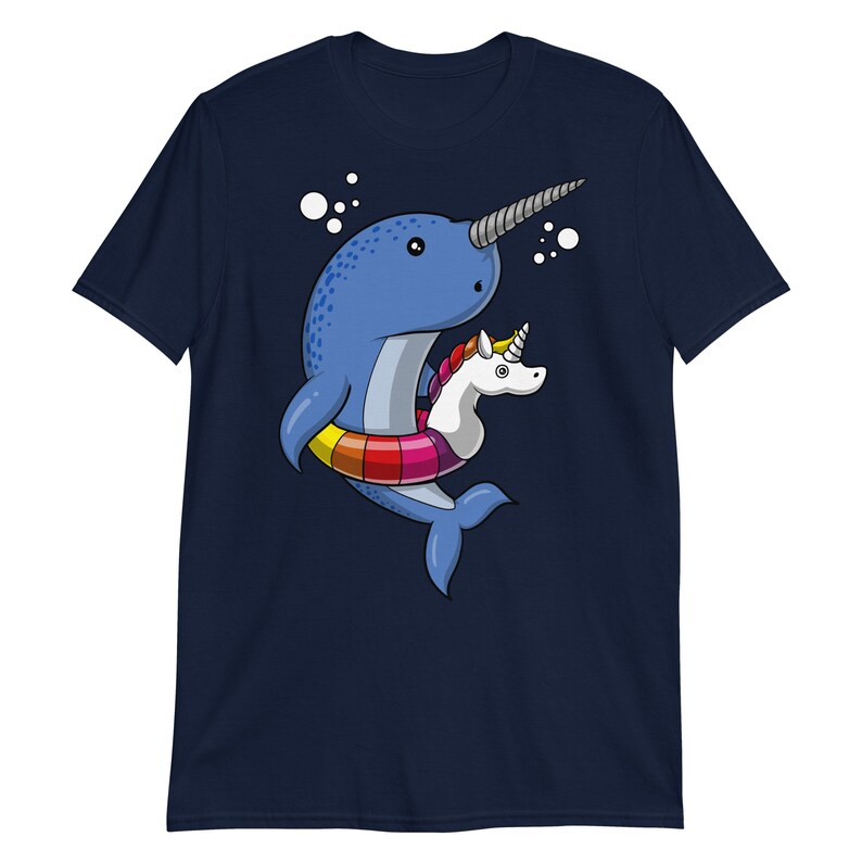 May include: A navy blue t-shirt with a cartoon illustration of a narwhal wearing a rainbow inflatable ring with a unicorn riding on top.