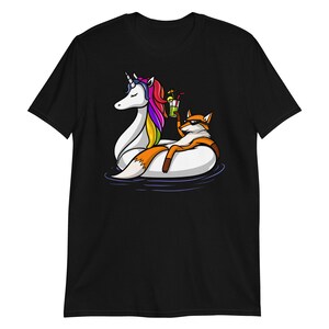 May include: A black t-shirt with a graphic of a fox wearing sunglasses and riding a unicorn float in a pool. The unicorn is rainbow colored.
