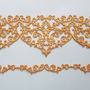 May include: Two decorative wooden cutouts with intricate, swirling patterns. The larger piece has a scalloped edge, while the smaller one is a straight line of repeating designs. Both are a warm, golden-brown color, perfect for home decor.