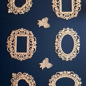 May include: Six gold-coloured metal frames with intricate designs, including oval, square, and round shapes, on a dark blue background.