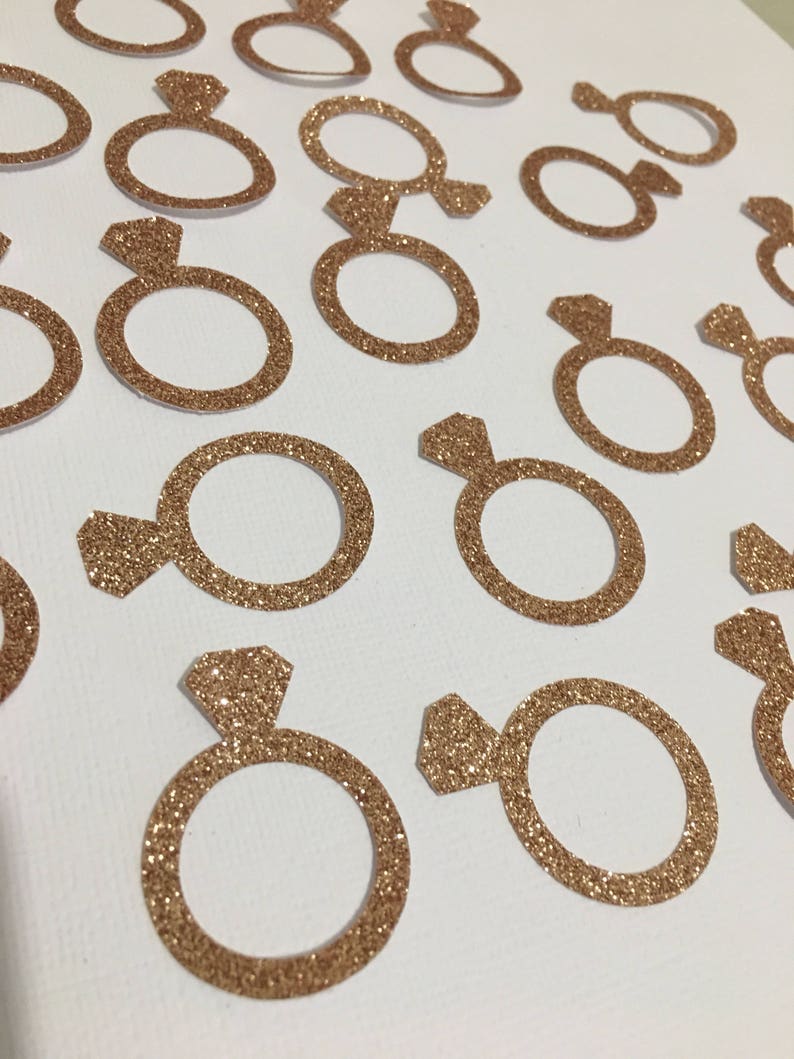 Puede incluir: Una colecci&oacute;n de confeti en forma de anillo de color dorado con purpurina, ideal para a&ntilde;adir un toque de brillo a la decoraci&oacute;n de una boda o una despedida de soltera.