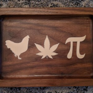 May include: A wooden rolling tray with a chicken, marijuana leaf, and the symbol for pi carved into it.