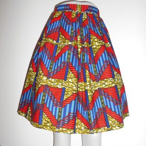 Peut inclure: Jupe au genou avec un motif géométrique vibrant. Le design présente des formes rouges, bleues et jaunes sur fond blanc. La jupe a une taille ajustée et une silhouette évasée, adaptée à diverses occasions.