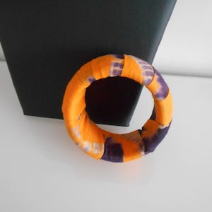 Könnte beinhalten: Ein Stoffarmband mit einem lila und orangefarbenen Batik-Muster.