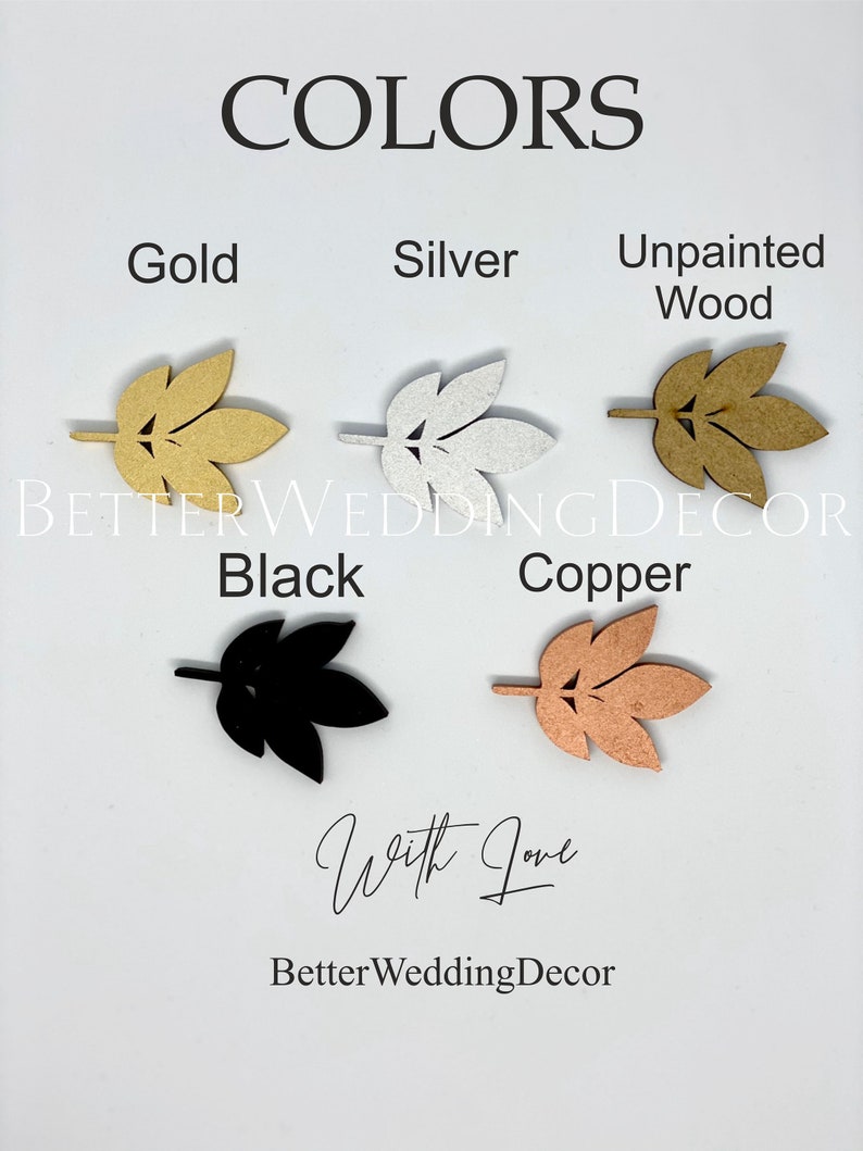 May include: A sample of different colors of wooden leaves, including gold, silver, unpainted wood, black, and copper. The leaves are arranged in a row, with the text "COLORS" above them and "BETTER WEDDING DECOR" below them.