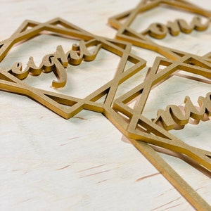 May include: Three gold geometric frames with the words "one", "eight", and "nine" written inside. The frames are made of wood and have a rustic look.