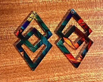 May include: A pair of colorful diamond-shaped earrings with a geometric design. The earrings are made of clear acrylic and feature a multi-colored pattern.