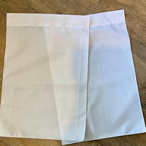 May include: Two white fabric panels with a sewn hem on the top edge. The panels are made of a lightweight, sheer material.